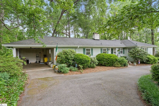 single story home with a carport, a chimney, and aphalt driveway