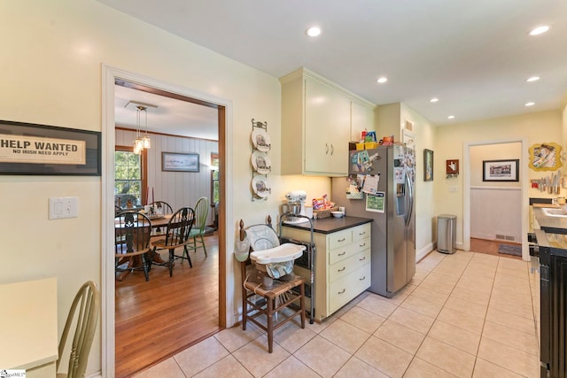 kitchen featuring dark countertops, recessed lighting, light tile patterned floors, stainless steel refrigerator with ice dispenser, and visible vents