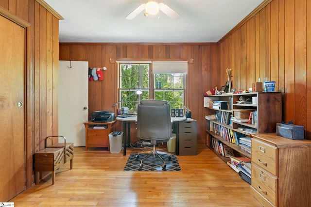 office featuring light wood-style floors, ceiling fan, and wooden walls