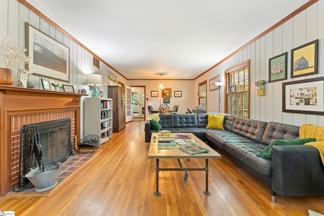 living room with crown molding, wooden walls, a brick fireplace, and wood-type flooring