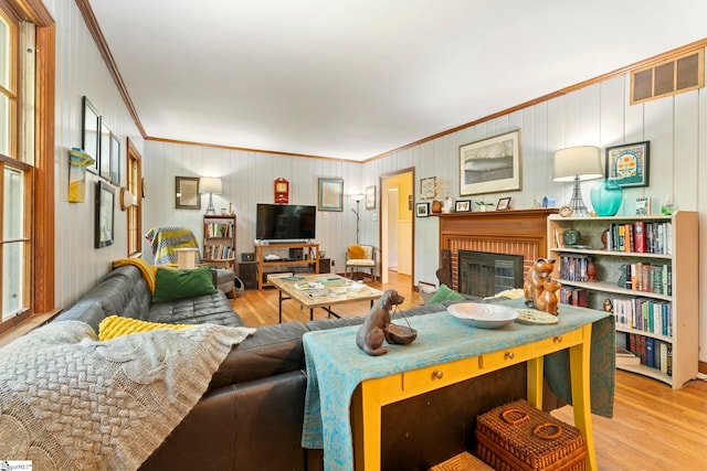 living area with crown molding, wood finished floors, and visible vents