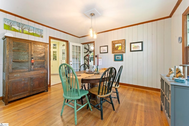dining space featuring baseboards, ornamental molding, and light wood-type flooring