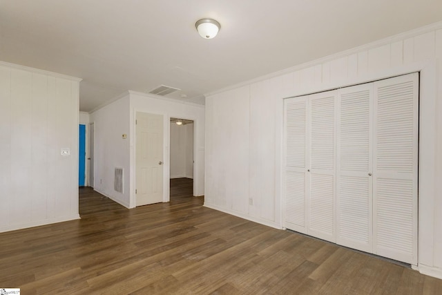 unfurnished bedroom featuring crown molding, a closet, wood finished floors, and visible vents