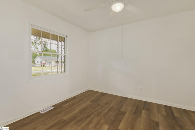 unfurnished room featuring baseboards, a ceiling fan, dark wood finished floors, and visible vents