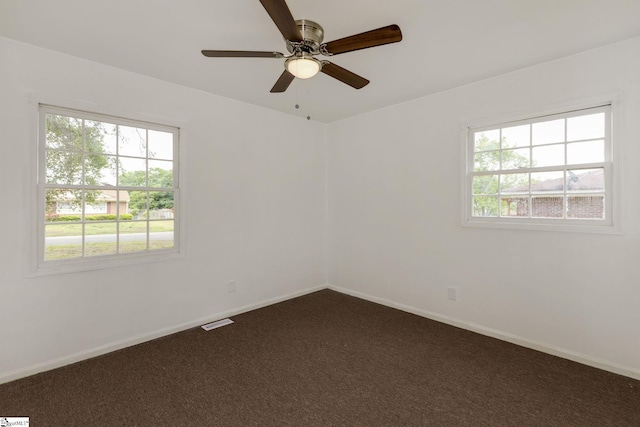 spare room with baseboards, ceiling fan, and dark colored carpet