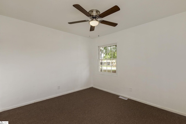 spare room featuring ceiling fan, visible vents, baseboards, and dark carpet