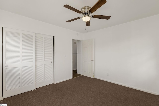 unfurnished bedroom with dark carpet, baseboards, ceiling fan, and a closet