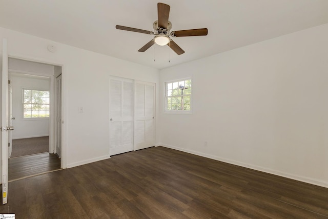 unfurnished bedroom with baseboards, ceiling fan, a closet, and dark wood-type flooring