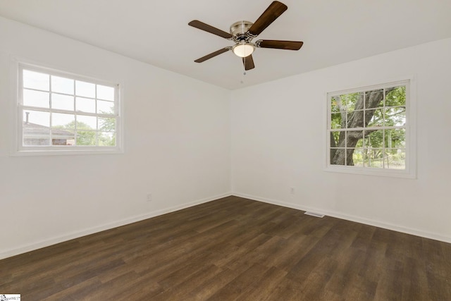 unfurnished room with baseboards, dark wood finished floors, ceiling fan, and visible vents