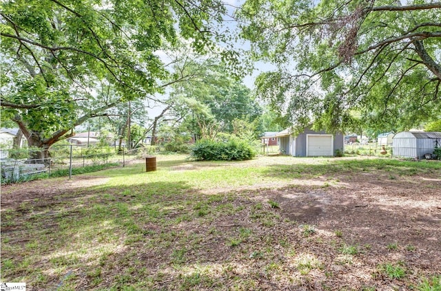 view of yard with a storage unit, fence, an outbuilding, and a detached garage