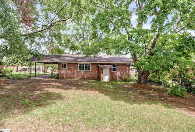 rear view of property with crawl space, a carport, brick siding, fence, and a yard
