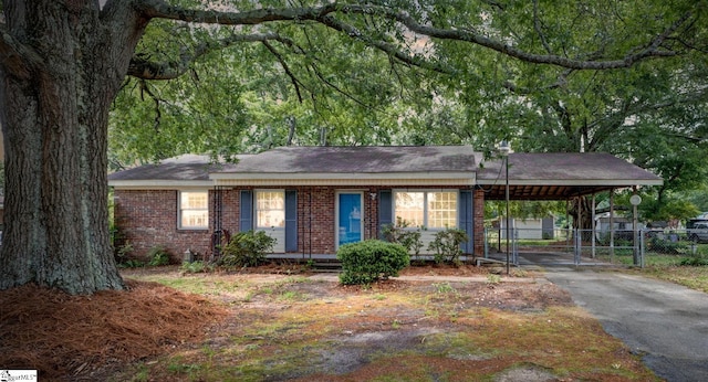 ranch-style house featuring fence, an attached carport, brick siding, a gate, and driveway