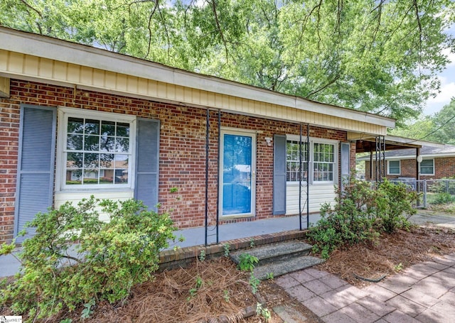 view of front of house with fence, a porch, and brick siding