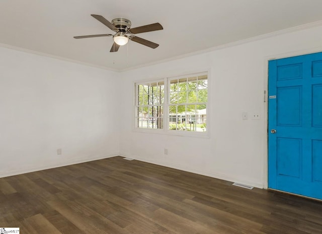 spare room with crown molding, visible vents, baseboards, ceiling fan, and dark wood finished floors