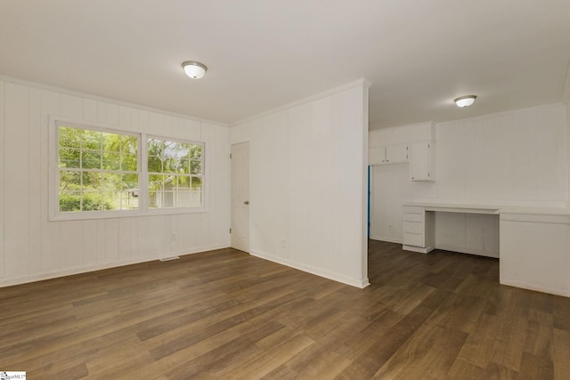 empty room with a decorative wall and dark wood-style floors