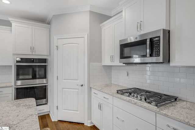 kitchen featuring ornamental molding, stainless steel appliances, white cabinetry, decorative backsplash, and dark wood-style floors