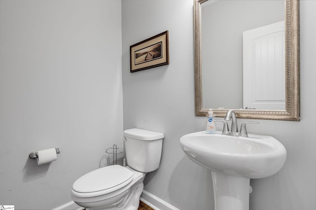 bathroom with baseboards, a sink, and toilet