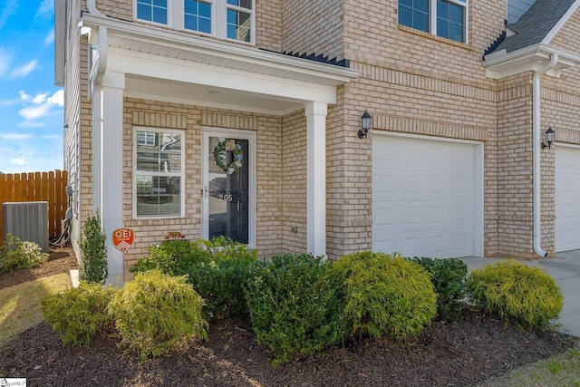 entrance to property with central air condition unit, fence, an attached garage, and a shingled roof