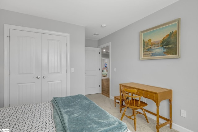 bedroom with baseboards, light colored carpet, and a closet