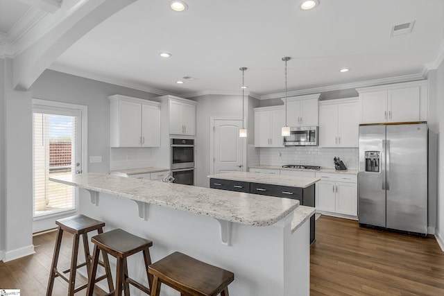 kitchen featuring arched walkways, a center island, stainless steel appliances, visible vents, and dark wood-style floors