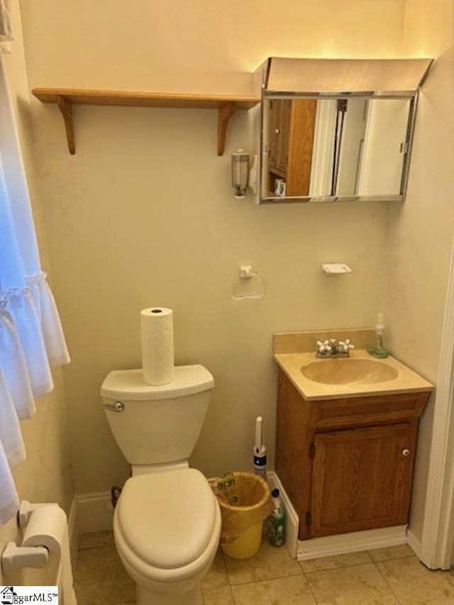 bathroom featuring vanity, tile patterned floors, baseboards, and toilet