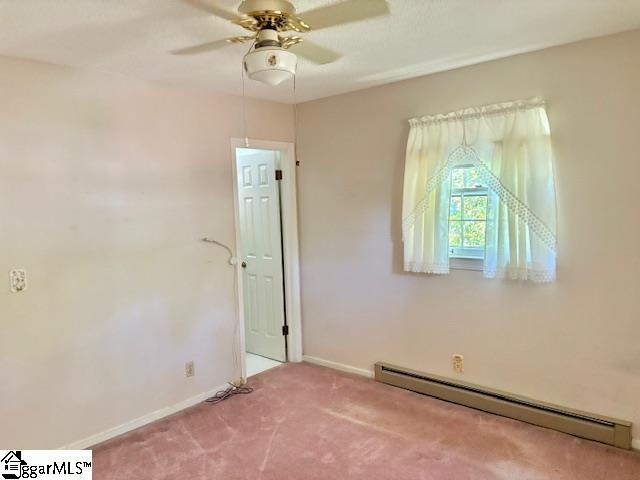 spare room featuring baseboards, a baseboard radiator, a ceiling fan, and carpet flooring