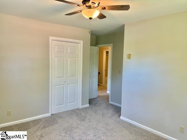 unfurnished bedroom with a closet, baseboards, ceiling fan, and light carpet