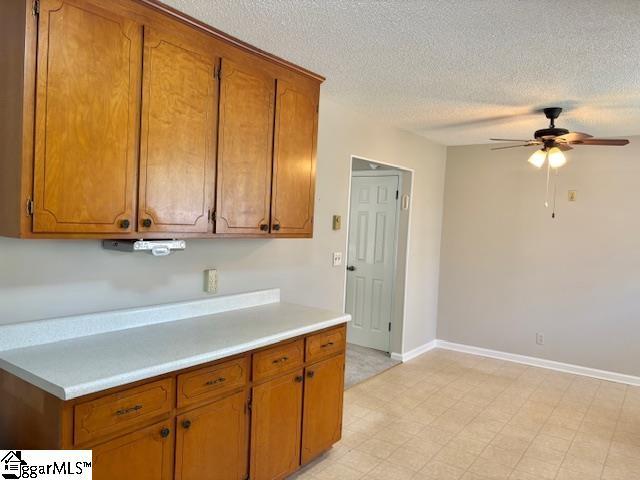 kitchen with light countertops, ceiling fan, and brown cabinets