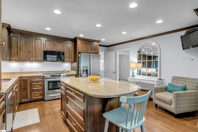 kitchen featuring a kitchen bar, stainless steel appliances, crown molding, light wood-style floors, and light stone counters