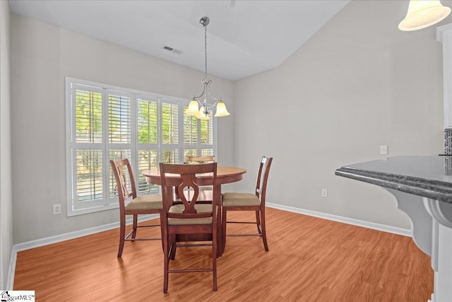 dining room with baseboards, visible vents, a chandelier, vaulted ceiling, and light wood-type flooring