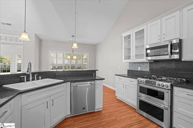 kitchen featuring a sink, stainless steel appliances, visible vents, vaulted ceiling, and dark countertops