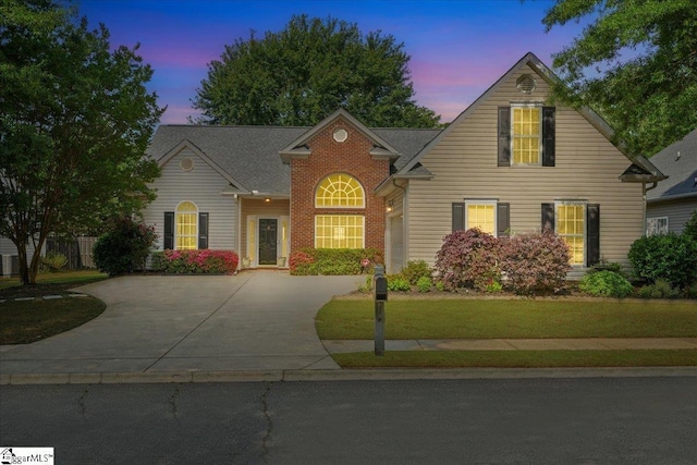 traditional home with concrete driveway, a garage, and a front yard