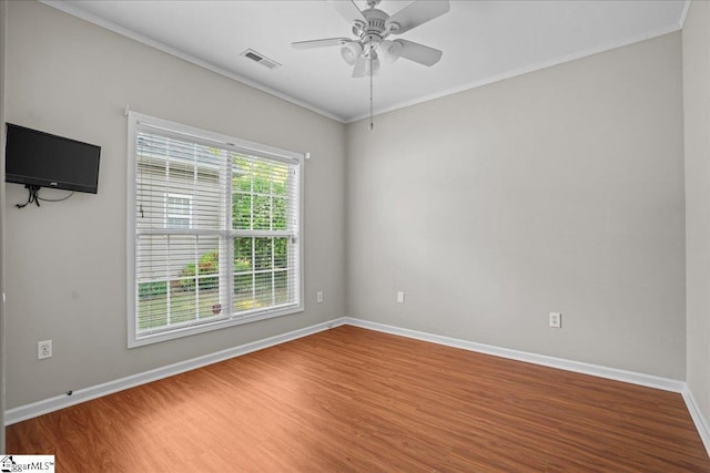 spare room with ceiling fan, ornamental molding, visible vents, and wood finished floors