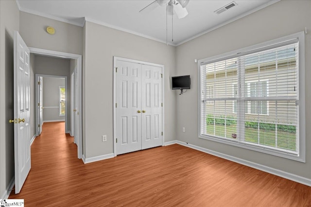 unfurnished bedroom featuring multiple windows, visible vents, and wood finished floors