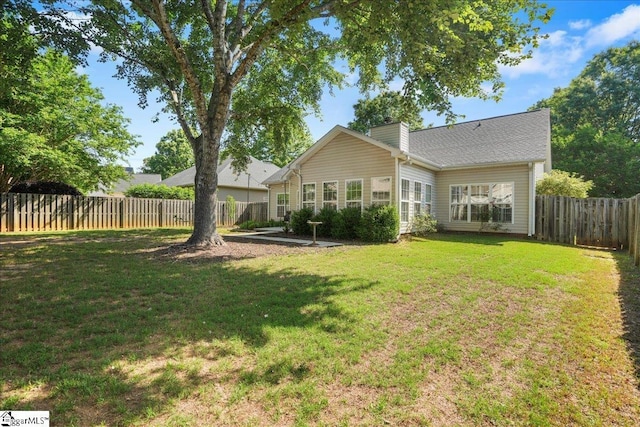 back of house with a yard, a chimney, and a fenced backyard