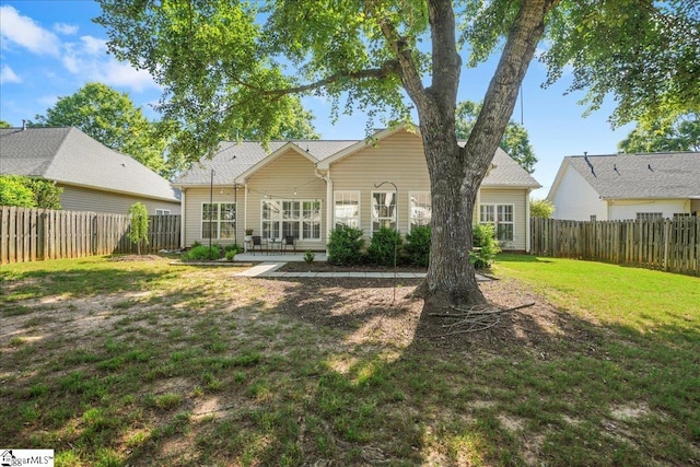 back of house with a yard and a fenced backyard