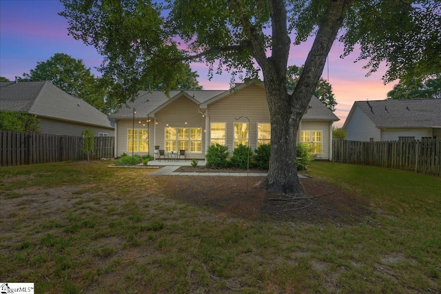 rear view of house with a yard and a fenced backyard