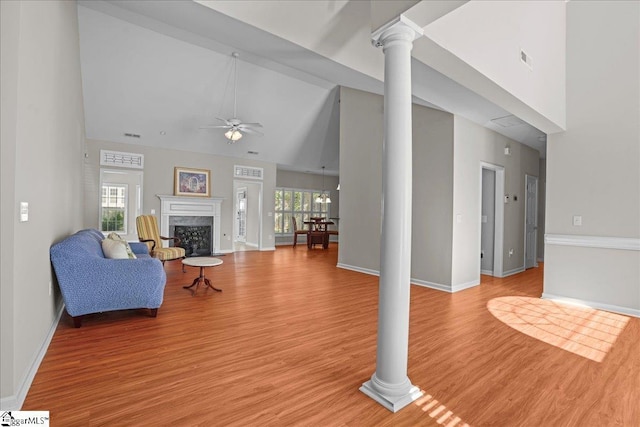 living room featuring high vaulted ceiling, light wood-type flooring, a ceiling fan, and decorative columns