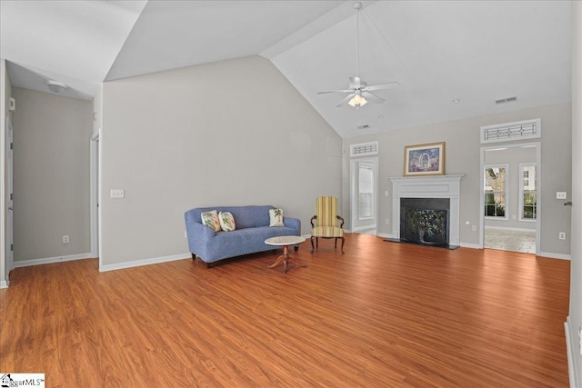 living area featuring wood finished floors, high vaulted ceiling, visible vents, a fireplace, and a ceiling fan
