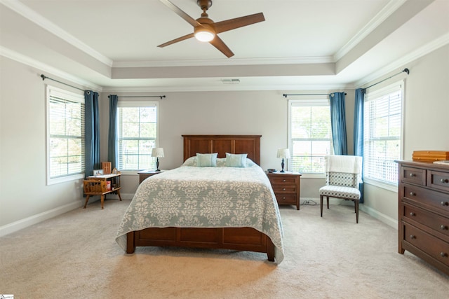 bedroom with a tray ceiling, multiple windows, and ornamental molding