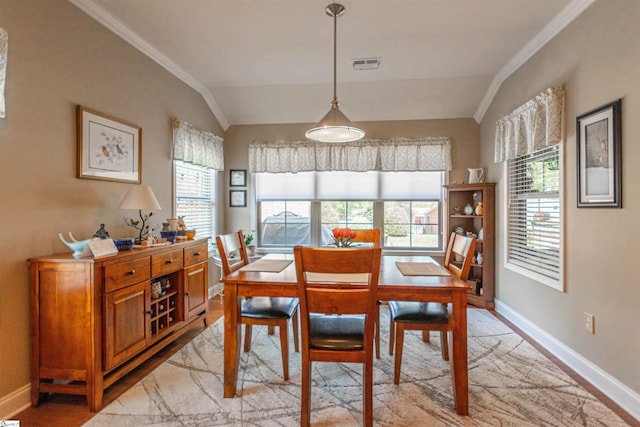 dining room featuring lofted ceiling, light wood-style flooring, baseboards, ornamental molding, and visible vents