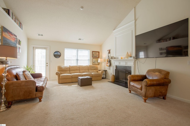 living area with a fireplace with flush hearth, visible vents, carpet, and vaulted ceiling