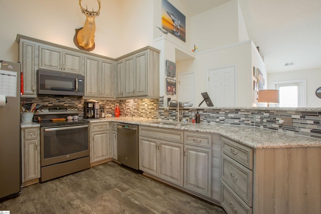 kitchen with visible vents, a sink, a peninsula, decorative backsplash, and stainless steel appliances