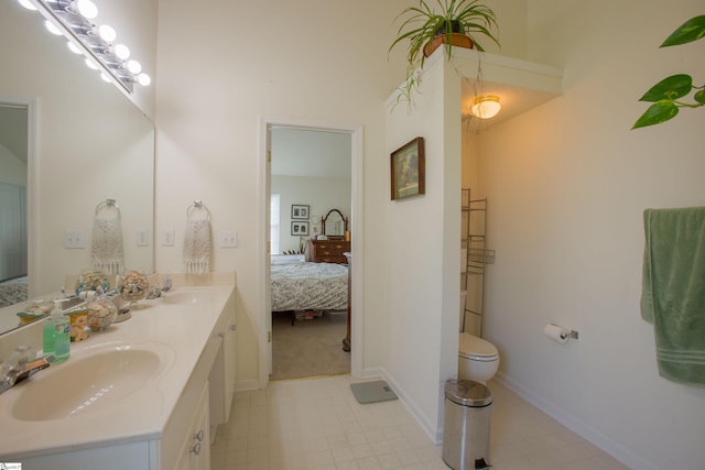 ensuite bathroom featuring a sink, double vanity, ensuite bathroom, and tile patterned floors