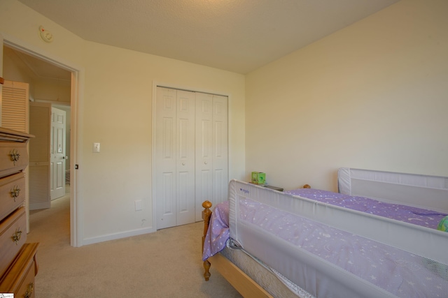 carpeted bedroom with baseboards and a closet
