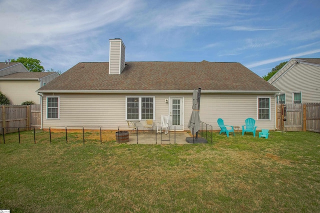 back of house featuring a lawn, a chimney, a patio, a fenced backyard, and a gate