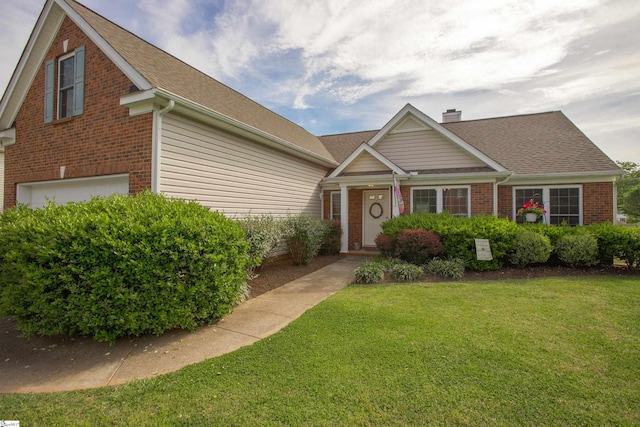 view of front of home featuring a garage, brick siding, a chimney, and a front yard
