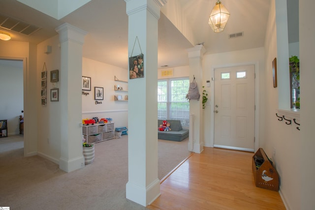 foyer with visible vents, baseboards, decorative columns, and light carpet