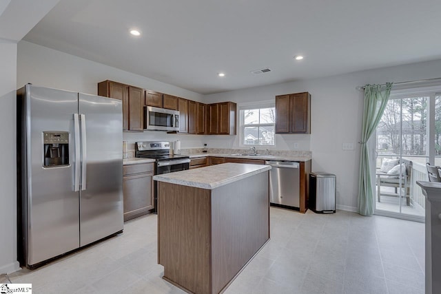 kitchen with stainless steel appliances, a center island, visible vents, a sink, and light countertops