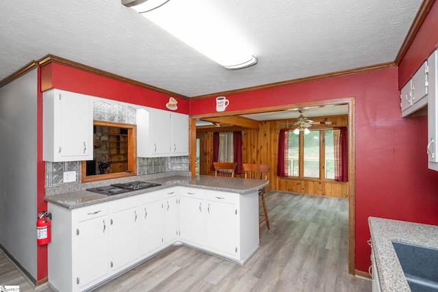 kitchen featuring ornamental molding, light wood-style flooring, white cabinetry, backsplash, and black electric cooktop